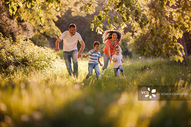无忧无虑的父母在户外追逐他们的小孩图片素材
