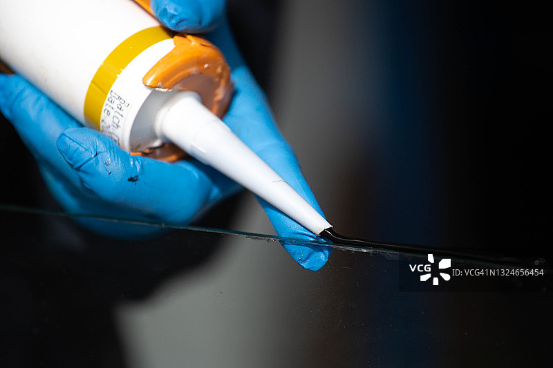 用硅胶和热熔胶枪紧密拉伸铝和玻璃特写图片素材