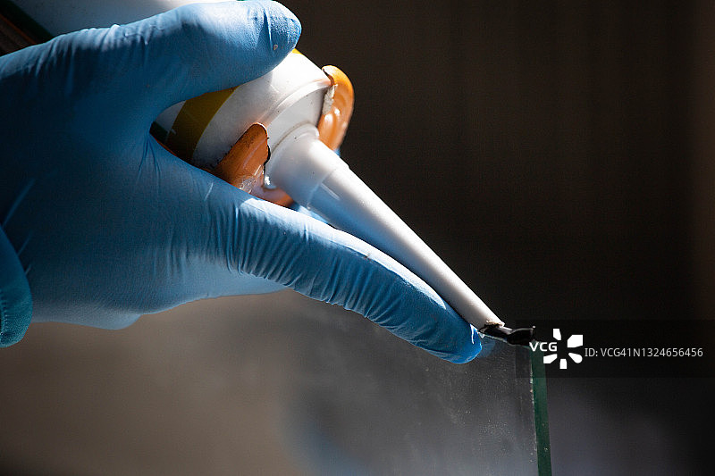 用硅胶和热熔胶枪紧密拉伸铝和玻璃特写图片素材