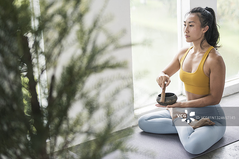 正在用颂钵冥想的亚洲瑜伽士图片素材