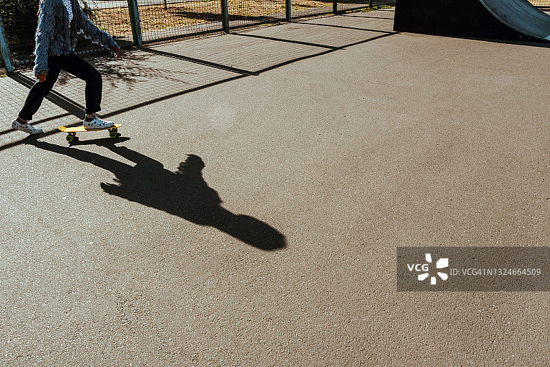 穿着牛仔裤和运动鞋的青少年站在滑板上，腿部特写图片素材