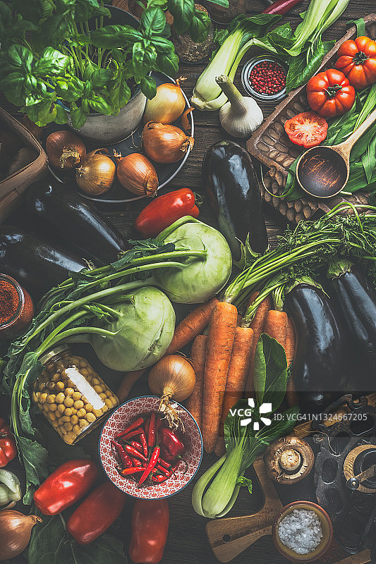 食物背景：乡村餐桌上各种健康的蔬菜、香草、香料和腌制食材，配有木勺，用于美味烹饪图片素材
