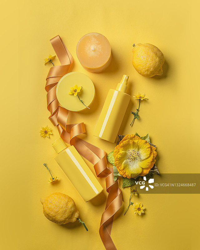 黄色有机化妆品概念：黄色泵装瓶，留白，蜡烛，柠檬，黄花和黄色背景上的环形胶带图片素材