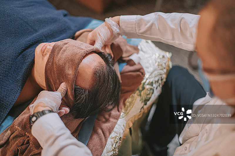 亚洲男性按摩师指压患者头部穴位缓解压力俯视图图片素材