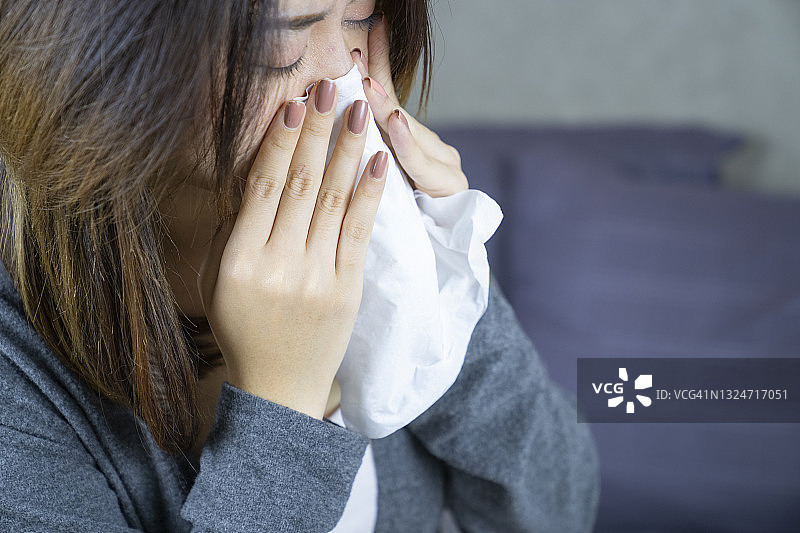 使用纸巾打喷嚏的亚洲女人特写图片素材