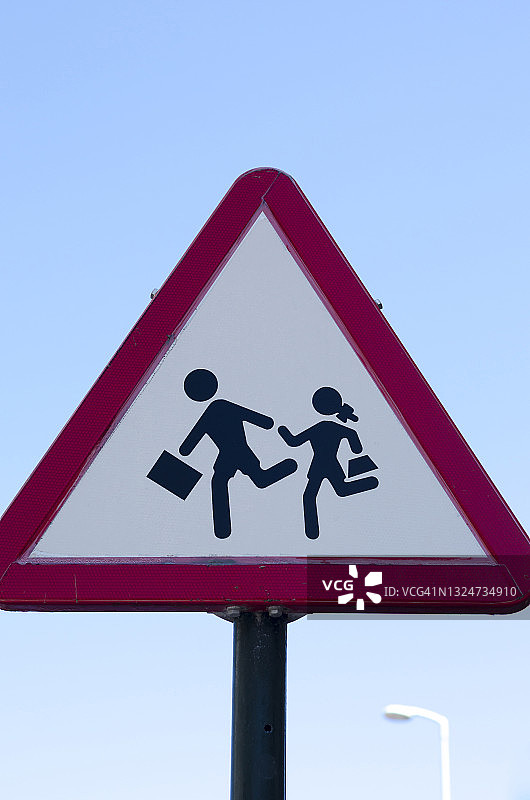 小学生在交通警告标志前过马路图片素材