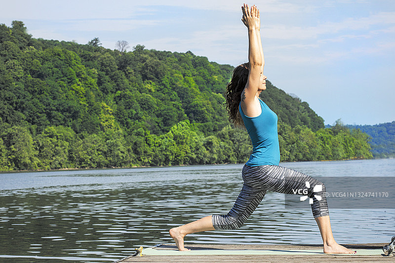 在河边做战士一式瑜伽的女人图片素材