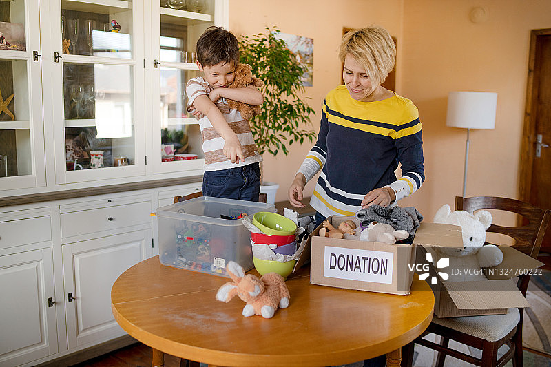 小男孩站在椅子上帮助母亲进行慈善捐赠图片素材