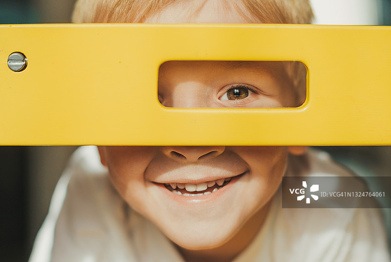 快乐的白人小男孩透过黄色框架微笑，学前教育、幸福家庭、育儿理念图片素材