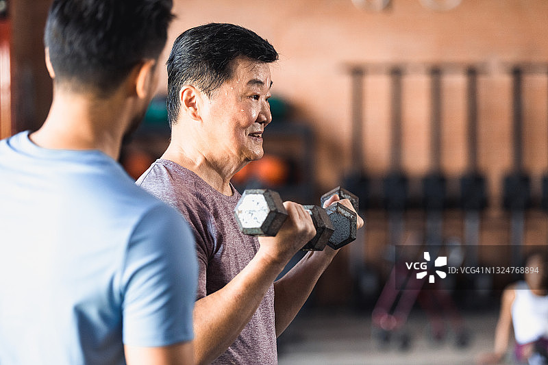 年长的男人专注地使用哑铃图片素材