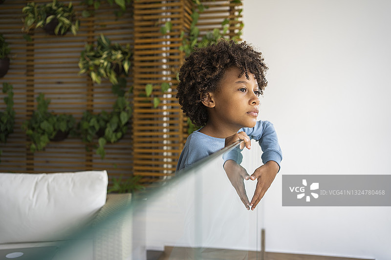 在新冠隔离期间，向外看的悲伤的非洲裔男孩图片素材