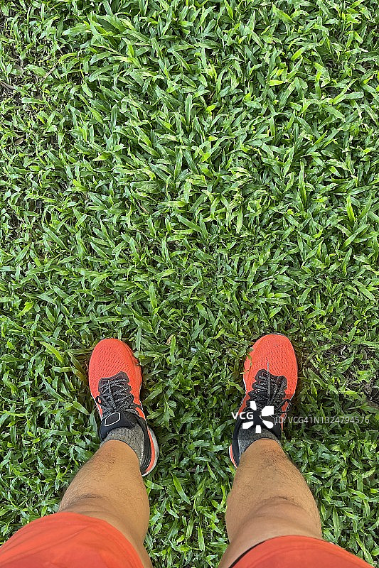 跑步背景：反光橙色跑鞋在龟裂水泥路面上图片素材