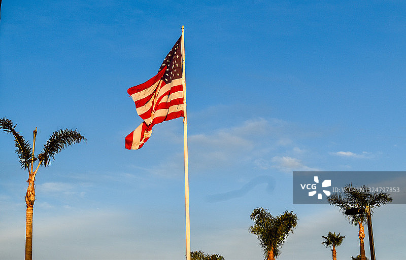 在白色旗杆上迎风飘扬的美国国旗图片素材