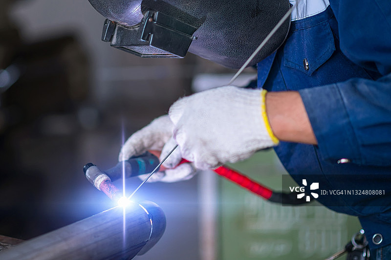 焊接工人在工厂焊接金属管图片素材