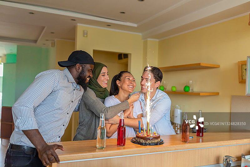 快乐的多元民族朋友在现代公寓放松身心，享受生日派对图片素材