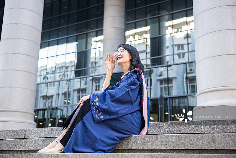 身穿毕业礼服坐在楼梯上的女学生肖像图片素材