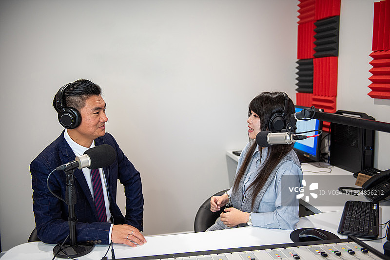年轻的亚洲女性主持人在广播工作室采访年轻男子图片素材