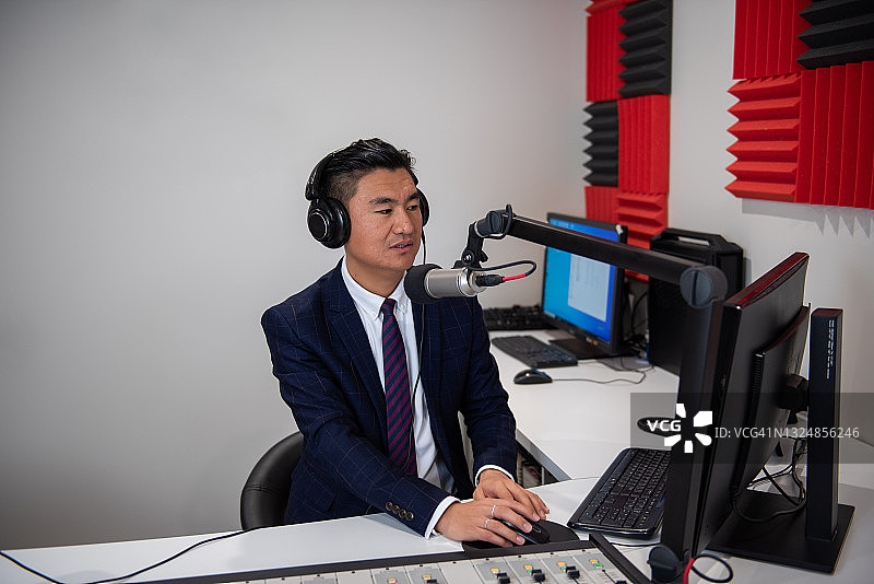 广播室里身着正装的年轻亚洲男主持人图片素材