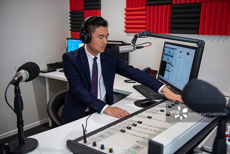 广播室里身着正装的年轻亚洲男主持人图片素材