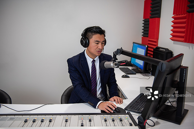 广播室里身着正装的年轻亚洲男主持人图片素材