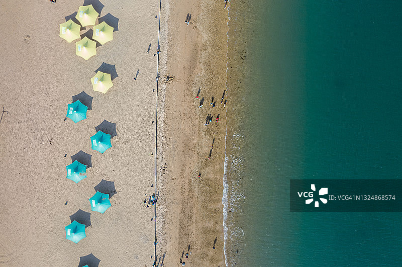 中国大连，沐浴在黄海中的黄色沙滩上的沙滩伞航拍景色图片素材