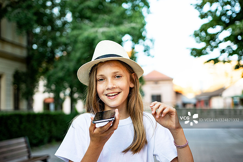城市街头，戴太阳帽的少女免提通话图片素材