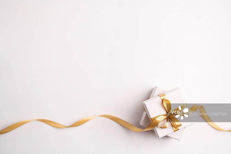 白色背景上的两个金色丝带白色礼品盒，顶视图图片素材
