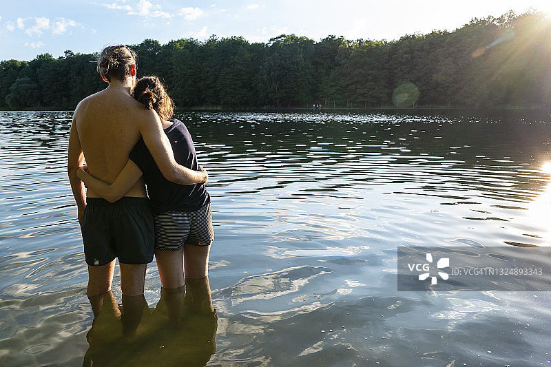 年轻情侣在湖边夏日恋爱的背影图片素材