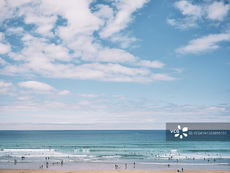 阳光明媚的六月，康沃尔郡纽基的菲斯特拉尔海滩景色，人们在海滩上冲浪图片素材