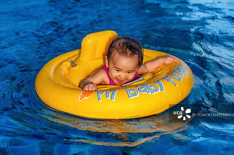 快乐的宝宝第一次在游泳池里戴着游泳圈游泳图片素材