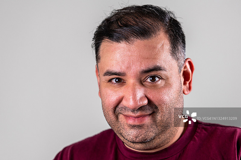 在灰色背景中微笑看着镜头的成熟男人图片素材