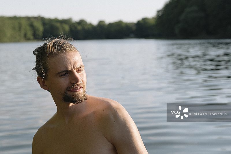 在湖边眺望远方的年轻男子夏日肖像图片素材