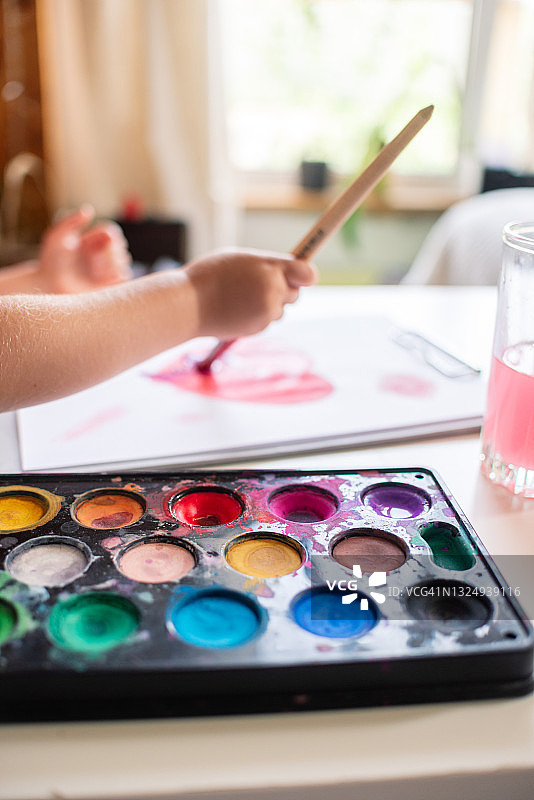 小孩子手持画笔颜料在纸上画心图片素材