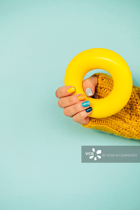 女人拿着黄色百吉饼，背景为浅蓝色图片素材