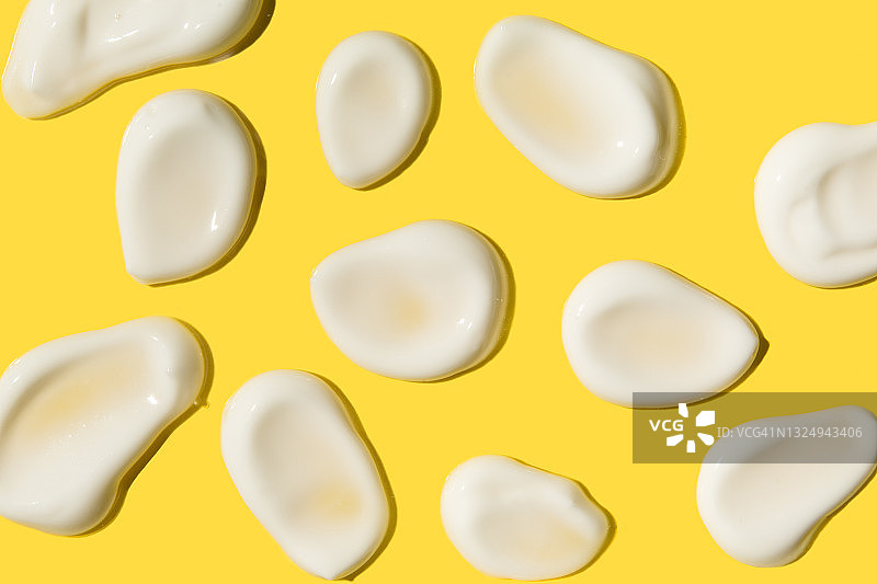 黄色背景上的白色奶油液体纹理涂抹，展平俯视图片素材