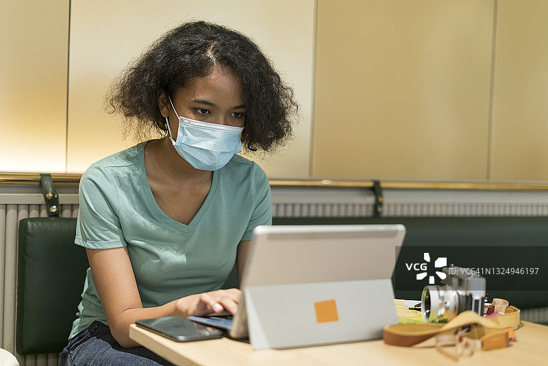疫情隔离期间在家用笔记本电脑的漂亮非洲裔美国女人图片素材
