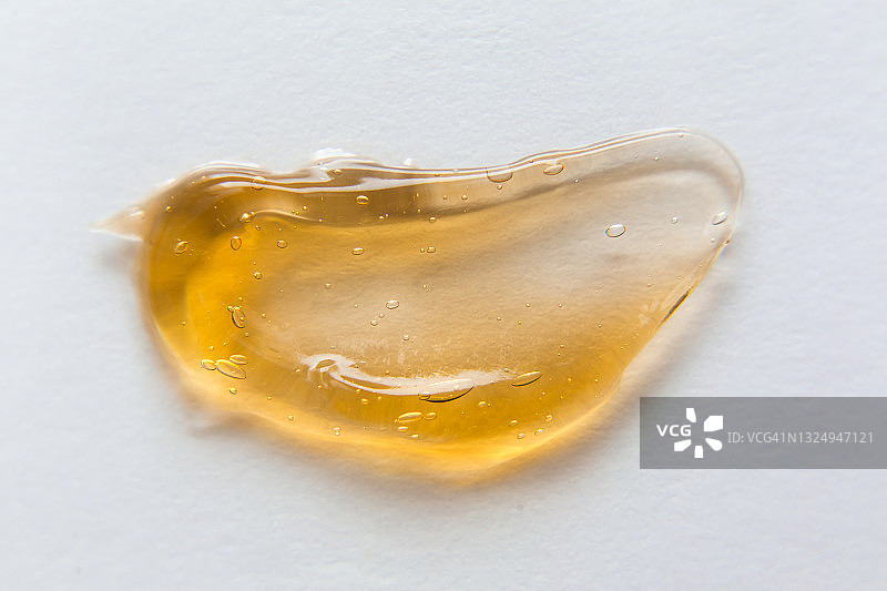 白色背景上的橙色凝胶透明涂抹，脱毛用黄色液体蜡或糖浆，无毛光滑肌肤脱毛概念banner图片素材