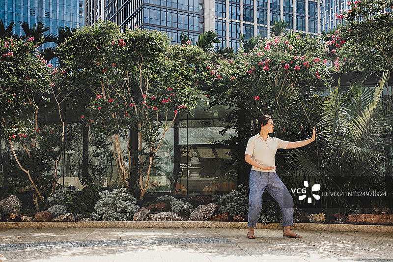 亚洲女商人在城市里练习太极拳图片素材