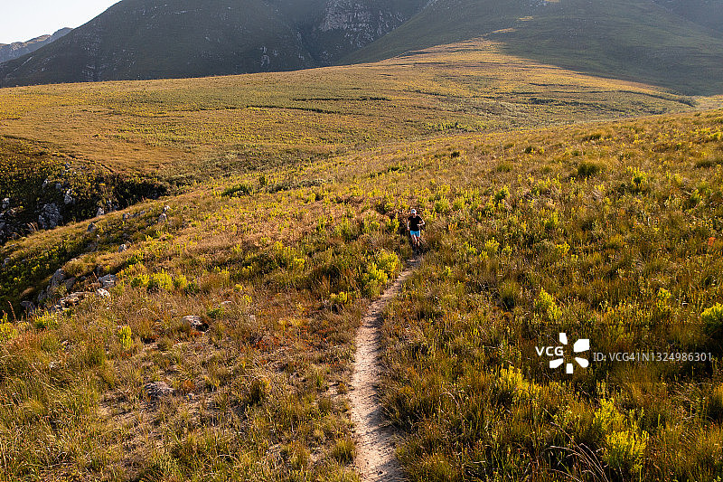 沿着山路跑步的健美女人图片素材