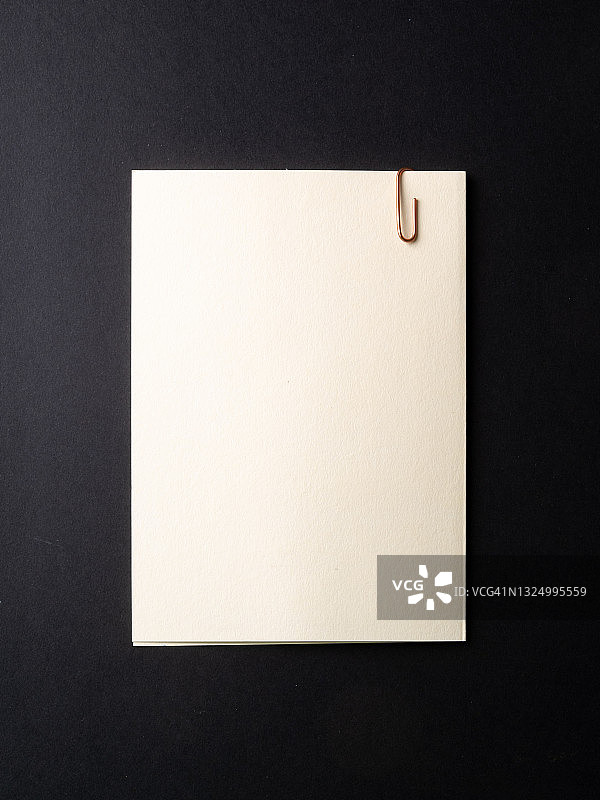黑色背景上的带回形针的空白便笺图片素材