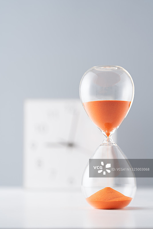 钟表前的橙色沙漏图片素材