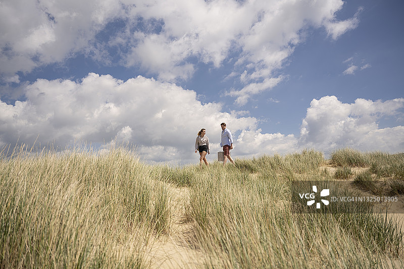 无忧无虑的夫妇带着野餐篮在沙丘上行走图片素材