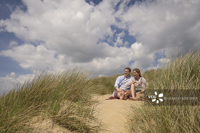 度假者斜躺在积云下的沙丘上图片素材