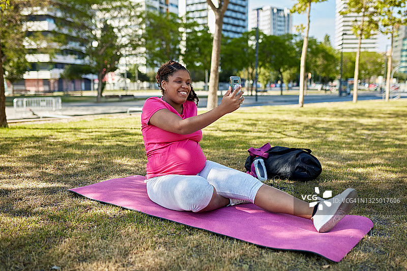 20多岁的孕妇在公园进行视频通话图片素材