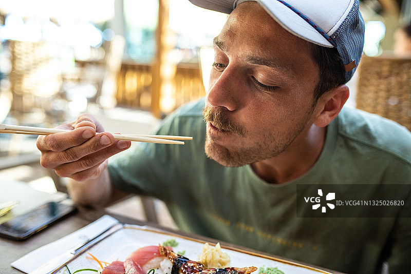 男人在户外餐厅吃美味的寿司图片素材