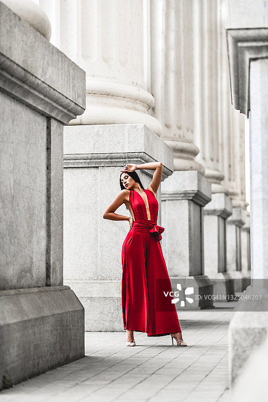 身穿红色优雅连衣裙站在大理石柱间的女人图片素材