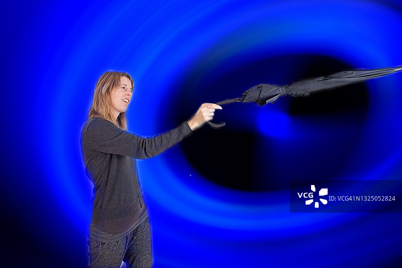 妇女将雨伞指向飓风或黑洞的中心图片素材