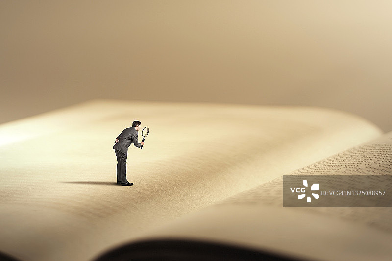 男人用放大镜看巨型书本图片素材