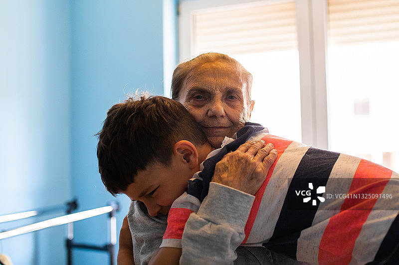 一位老妇人快乐地笑着，她的曾孙拥抱着她图片素材