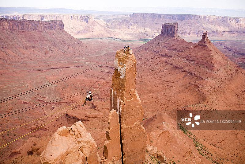 冒险赛车手在犹他州摩押沙漠上方的高空滑索上比赛图片素材